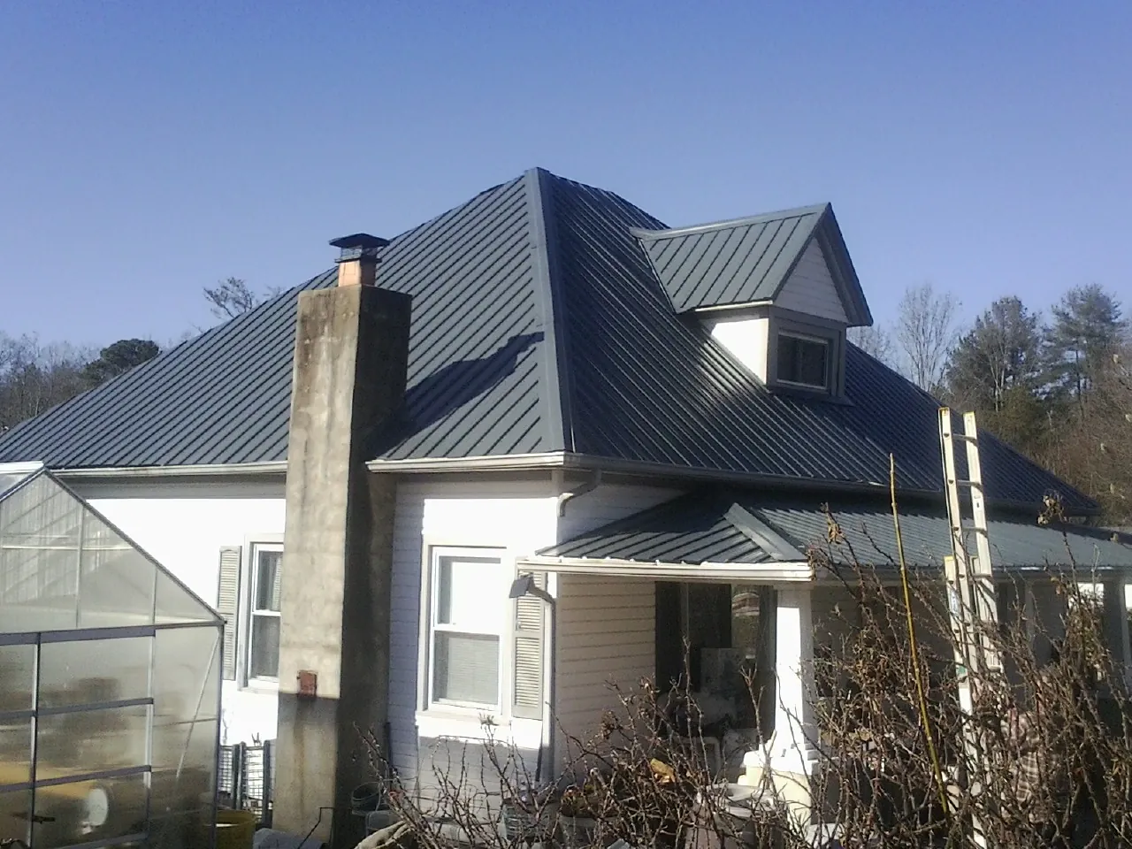 Dark blue standing seam metal roof on a white farmhouse with dormer — Slate & Tile Roof Repair by Roofing Brothers in Dolphin