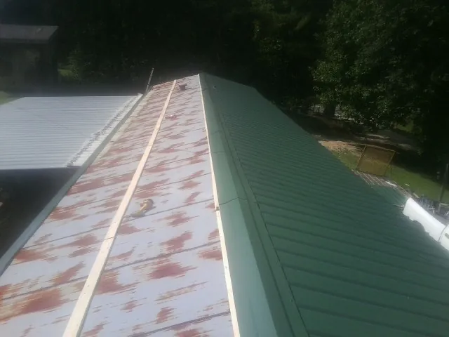 Old rusted panels beside newly installed green metal roofing — Wind Damage Roof Repair by Roofing Brothers in Dolphin