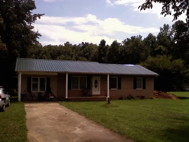 Dark green metal roof on a brick ranch with a covered porch in Dolphin