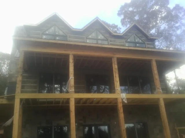Dormers and porch framing on a large log home under construction — Roof Coating work by our crew in Dolphin