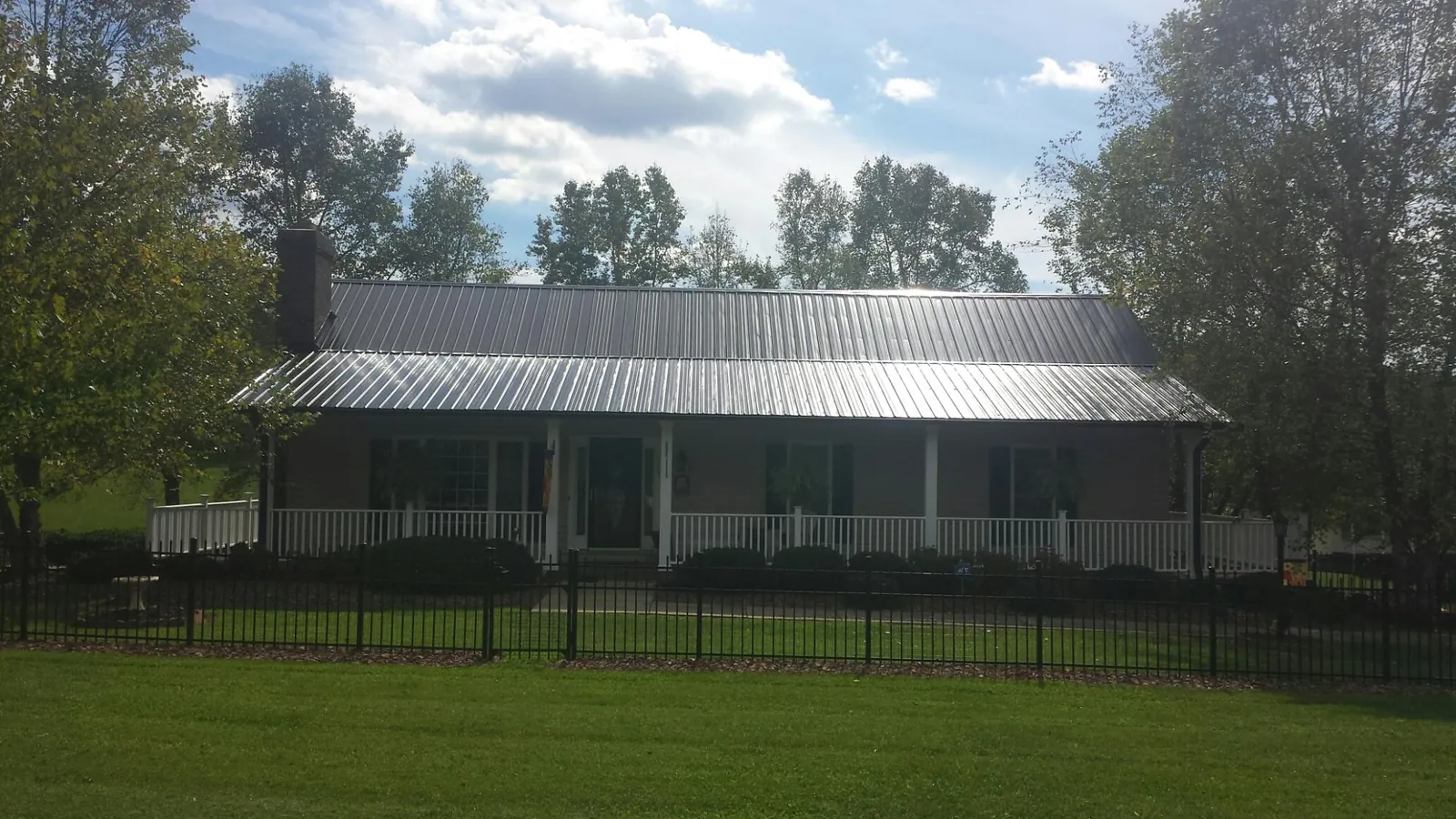 Gray metal roof on a brick ranch with a full width front porch — Gutter Guard Installation work by our crew in Dolphin