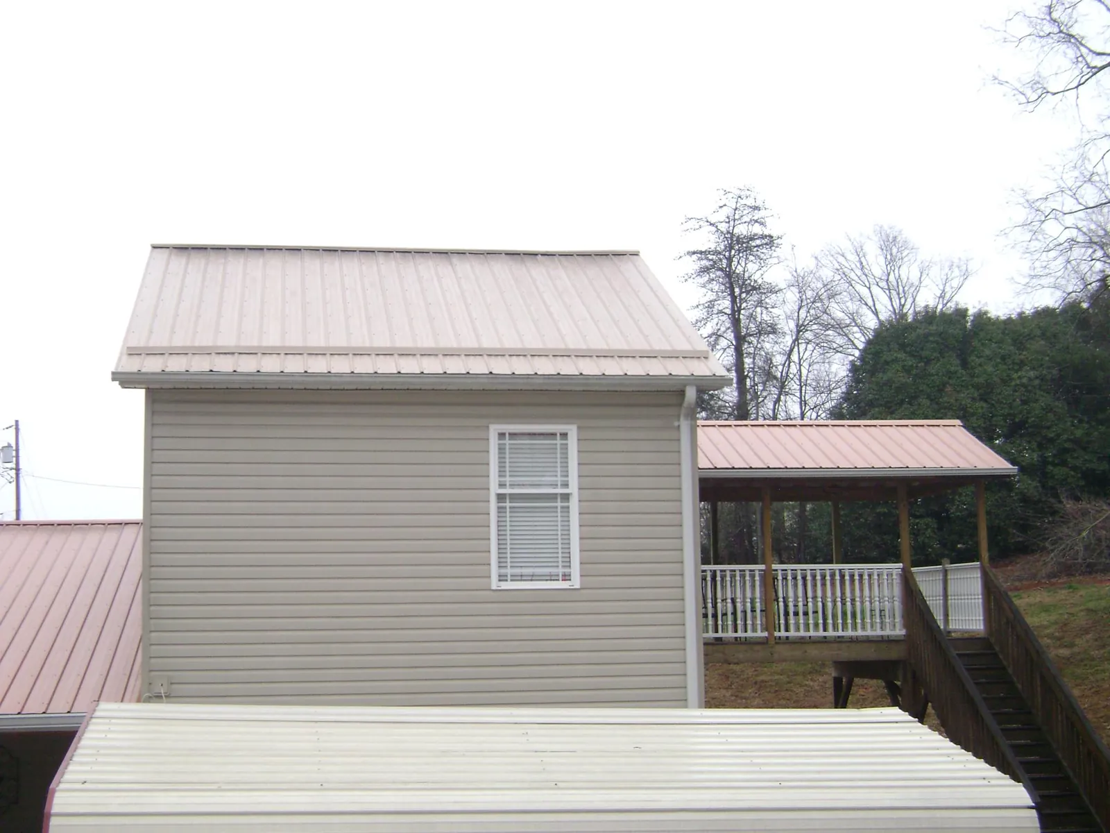 Tan metal roofs on a two story addition and attached porch, from a Roof Replacement job in Dolphin
