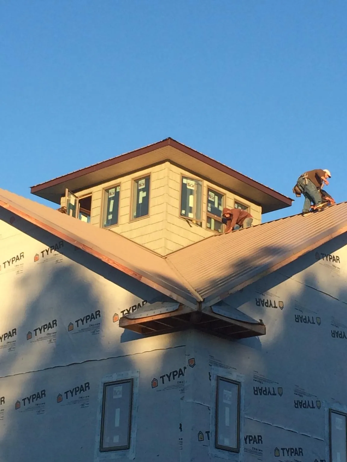 Roofers working around a rooftop cupola on a new metal roof at sunset — Roof Waterproofing in Dolphin by Roofing Brothers